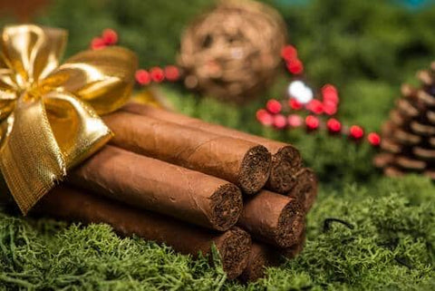 Cigars laying on top of Christmas decorations